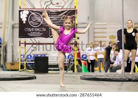 Perm, Russia - April 25, 2015. Championship Perm region at pole sport and dance. Child in pink suit with two tails makes vertical split