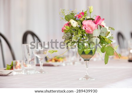 Flower arrangement of white roses and ivy is a crystal glass on the table