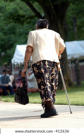 Old lady walking up a  hill with  cane