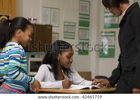 African American student gets help from teacher while another student look at the math problem