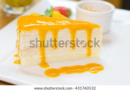 crepe cake with mango sauce. Orange crepe cake. set on white plate.