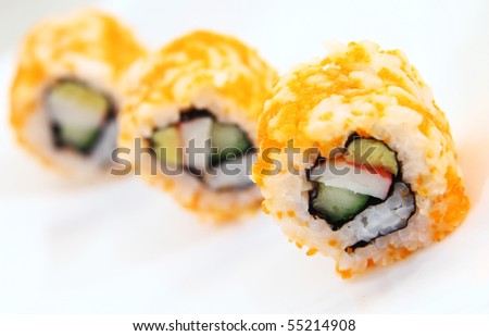 Japanese sushi covered in orange shrimp roe, arranged in single file and served on a white platter.