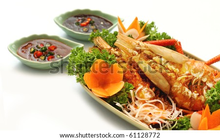 Thai style golden river prawn with garlic and pepper, served with exotic sauce on green plate and white background