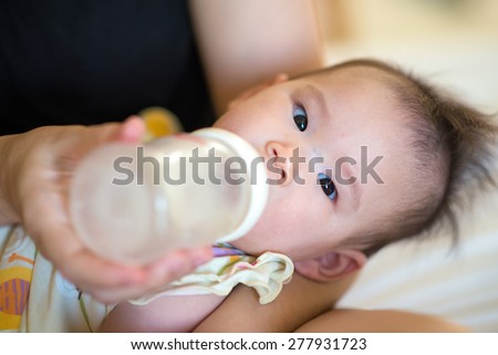 Mother holding a baby and feeds with a baby bottle