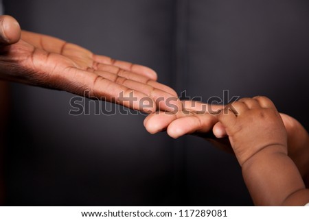 An african father\'s hand coming together with mother and baby