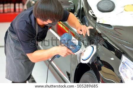 The man is polishing the black car with polish machine.