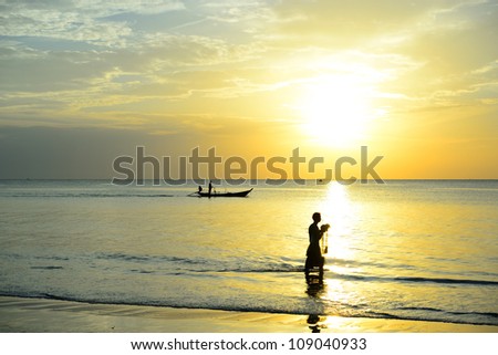 Fisherman are taking fishing boat to fish and a man hold the net to fish with sunrise background in thailand.