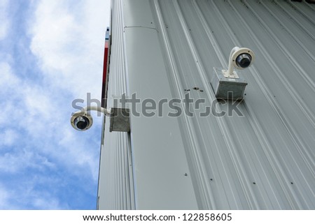 Security cameras are install corner outside of building with blue sky backdrop