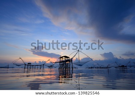 silhouette traditional fishing method using a bamboo square dip net with sunrise background in Patthalung, Thailand