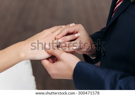 groom wears a wedding ring on the finger of the bride gold