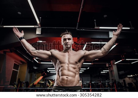 Beautiful sport bodybuilder man on a diet, weight training with dumbbells pumping muscle.With six pack, perfect brakes, shoulders, biceps, triceps and chest.Young adult doing weight lifting at the gym