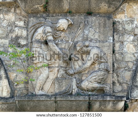 Bas-relief of a woman and a warrior on the stone wall.