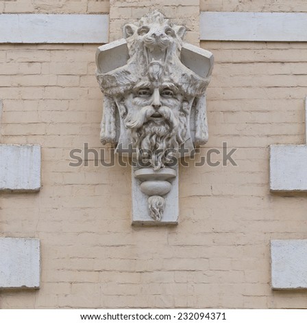 Plaster masks in the form of a bearded male face on a brick wall of the building.