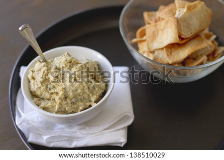 Artichoke hummus with pita chips on a plate.