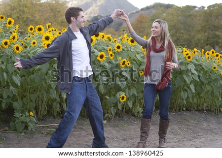 A young couple dances near sunflowers.