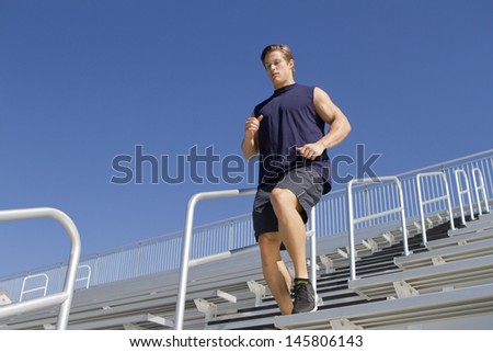 A Caucasian man in his twenties works out at a stadium.