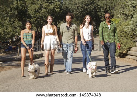A group of friends walking their dogs down to the lake.
