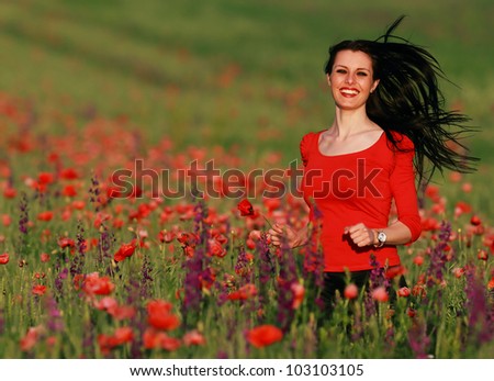 Young brunette beautiful girl running in a field of poppies