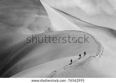 Team of three alpinists climbing a mountain