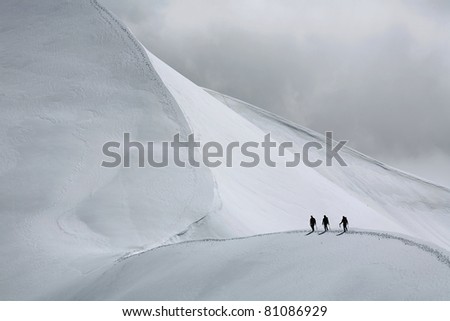 Team of three alpinists climbing a mountain