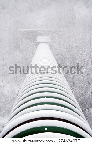 Industrial pipe over an alpine valley. Harsh winter conditions.