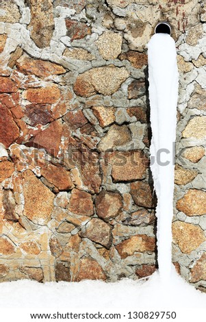 Old drain pipe with frozen water against the wall