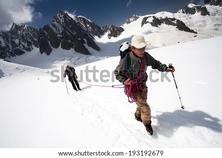 Team of two alpinists climbing a mountain during foggy weather
