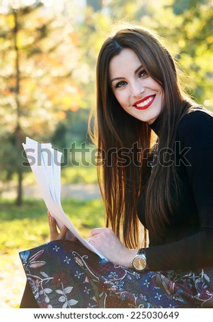 Young brunette girl studying in the park - autumn colors