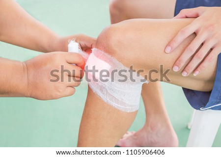 Nurse wounding bandage around knee of patient