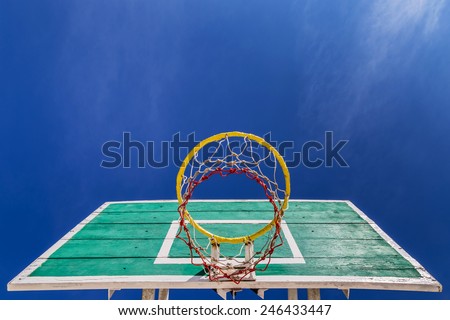old green basketball board with yellow hoop on blue sky background