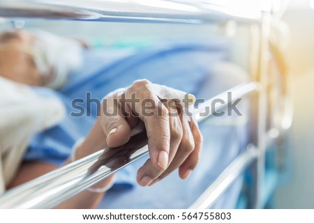 Close up hand of elderly patient with intravenous catheter for injection plug in hand during lying in hospital ward room