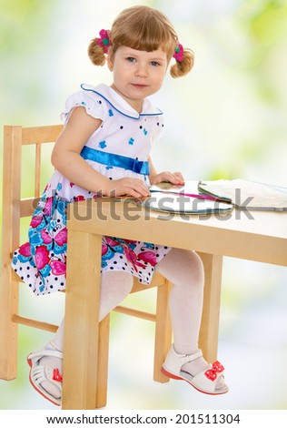 The girl sitting at the table with books.child, happiness and people concept, lovely smiling toddler portrait