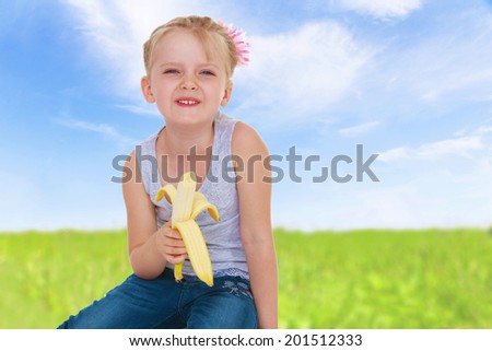 Girl with banana on nature background.spring season,fun outdoors,happy childhood,sweet child having fun outdoor,smiling toddler portrait