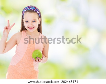 Girl showing thumbs up sign of victory and holding a green apple.healthy food concept,active lifestyle,happiness concept,carefree childhood concept.