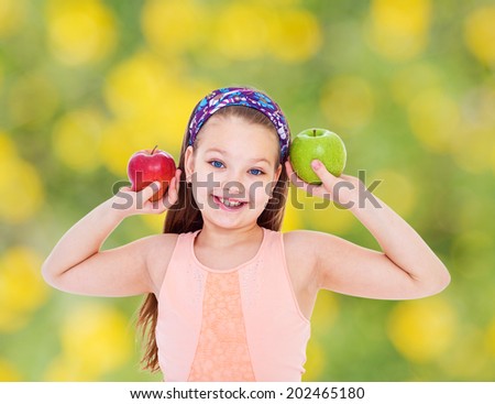 girl holding two apples and smiling at the camera.healthy food concept,active lifestyle,happiness concept,carefree childhood concept.
