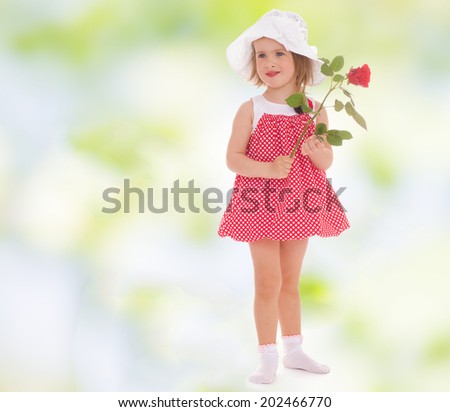 charming little girl in a red sundress and a red rose in his hand.active lifestyle,happiness concept,carefree childhood concept.