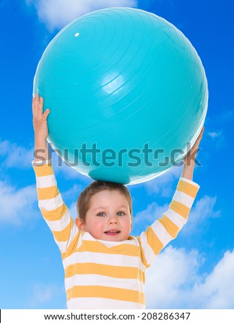 Boy holding up a huge blue ball on a background of blue sky.the concept of childhood and joy, teens