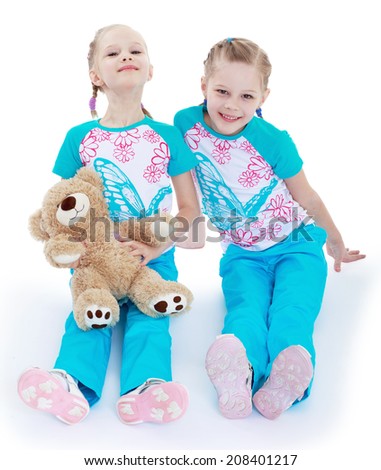 funny sisters with a teddy bear on a white background.kindergarten, the concept of childhood and joy, teens
