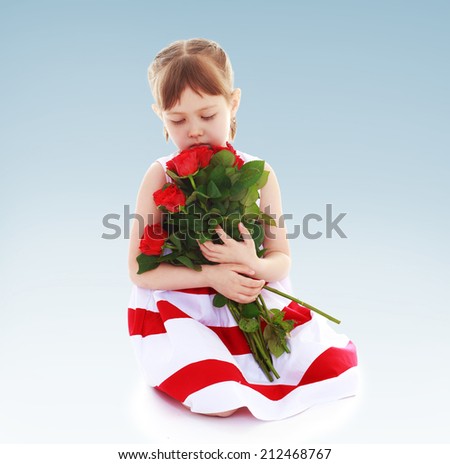 sweet girl smelling a bouquet of red roses.The concept of child development, education, recreation