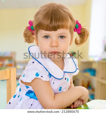 Girl sitting at the table looking at the camera.The concept of a child learning and development.