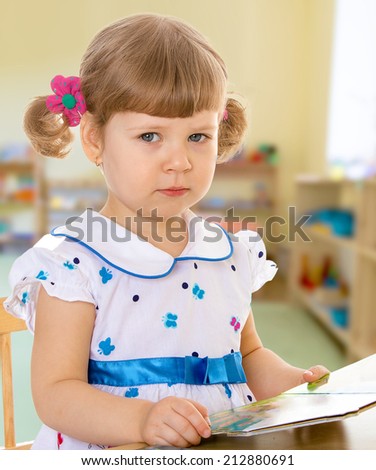 Girl reading a book while sitting at table.The concept of a child\'s learning and development.