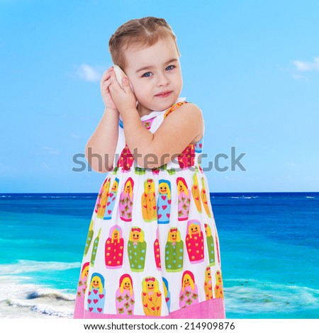 charming girl on the beach listening to a noise shell attaching it to his ear.
