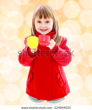 Charming little girl in a red coat with plastic toys in the hands Happiness, winter holidays, new year, and childhood.