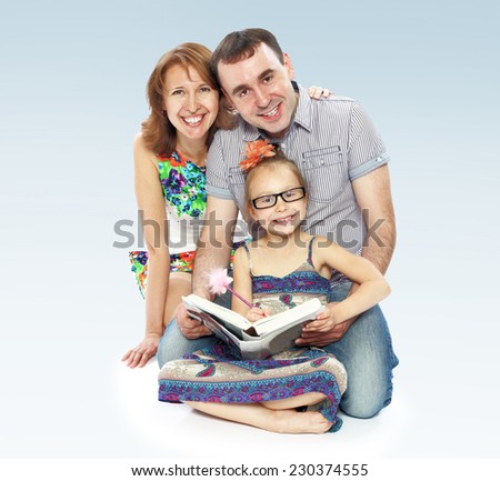 Family of three mom dad and daughter reading a book.