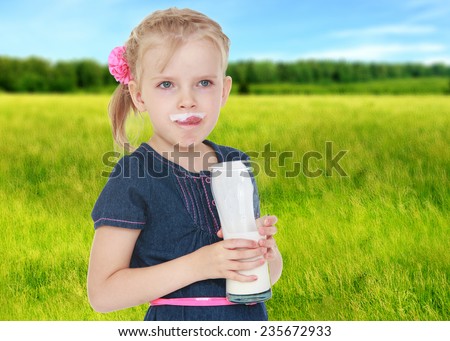little girl smeared with milk licking lips that language.Summer background.