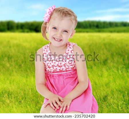 Little girl sitting on his lap in a big green grass on a summer meadow .Summer background.