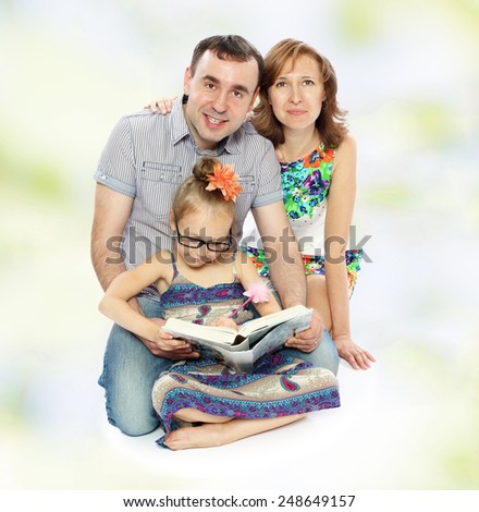 Very positive young family, mom dad and daughter reading a book with enthusiasm
