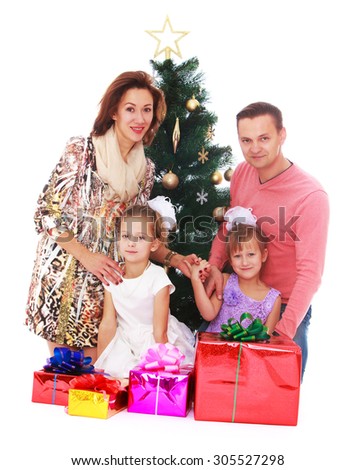 Happy family mom dad and two adorable daughters around the Christmas tree. Next to the Christmas tree are beautifully packaged in gift boxes-Isolated on white background