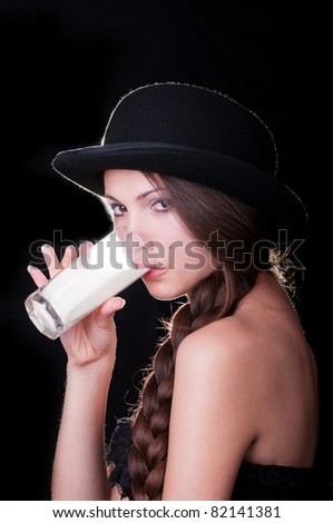 Young woman wearing a stylish corset and a vintage hat drinking milk