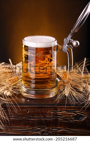 Mug of light beer on a wooden chest with barley ears